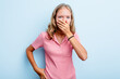 Caucasian teen girl isolated on blue background covering mouth with hands looking worried.
