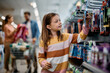 © Drazen - Smiling schoolgirl choosing products at school supplies section in supermarket.