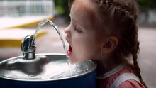 Toddler Baby Girl Quenches The Thirst With Drinking Water Fountain At The Park