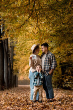 Happy Family Of A Man With A Woman Holding An Ultrasound Pregnancy Picture And A Surprised Son Who Will Be The Older Brother. Autumn Photo Shoot Of A Family Waiting To Be Replenished