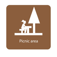 Picnic Area Sign With A Girl Sitting On A Picnic Table Under A Tree