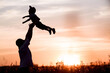 © Юлия Клюева - Father and son play in the park during sunset. People have fun in nature. Dark silhouettes of people on an orange background.The concept of a friendly family and summer holidays and Father's Day.