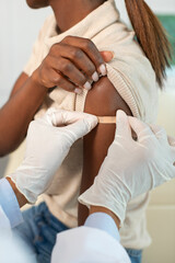 close-up of hands of nurse in protective gloves applying plaster to female arm. doctor putting patch