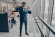 © VK Studio - Young amazed businessman in VR headset trying to touch something with hands while standing in modern office