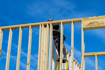 Wall Mural - Using an air hammer, a builder nails wooden beams to the wall as part of his work in construction house