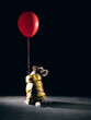 A dog in halloween costume based on The It, a dog in a yellow coat and with a red balloon