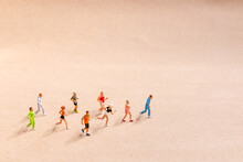 Miniature People Exercising While Running In A Group On The Beach. Living An Active Lifestyle Concept