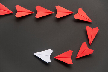 Wall Mural - White paper plane origami leading red planes on dark background. Leadership skills concept