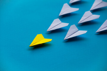 Wall Mural - Yellow paper plane origami leading white planes on blue background. Leadership skills concept
