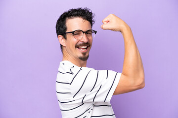 Young caucasian man isolated on purple background With glasses and celebrating a victory