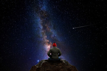 Wall Mural - man sitting on top of a mountain, observing the universe