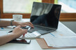 © PHAISITSAWAN - Business woman holding pen to present profit data in graph to supervisor via laptop computer.