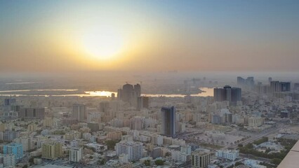 Wall Mural - Sunrise with cityscape of Ajman from rooftop aerial timelapse. Sun over modern city. Ajman is the capital of the emirate of Ajman in the United Arab Emirates.