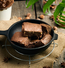 Canvas Print - Baked pieces of chocolate brownie cake with walnuts in a black metal frying pan