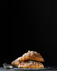 Canvas Print - Baked croissant on a  board and sprinkled with powdered sugar, black table. Appetizing pastries for breakfast.