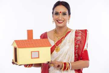 Wall Mural - Happy bengali woman holding model house in traditional sari
