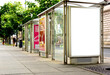 bus shelter at tram and bus stop. image collage. white poster ad display. advertising concept. glass and steel design. blurred color posters. urban setting with green trees in the background