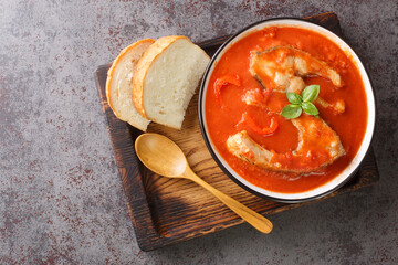 Fish tomato soup with carp steak, vegetables and paprika close-up in a bowl on the table. Horizontal top view from above