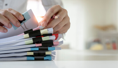 Businessman hands working on Stacks of paperwork for on his desk at home, work from home concept, business report, piles of unfinished documents, closeup view.
