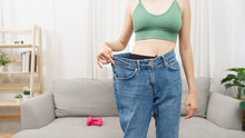Healthy And Weight Loss Concept, Young Asian Woman In Loose Jeans When Success With Losing Weight