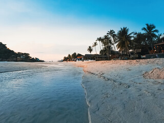  Tropical resort with trees and white beach sand.