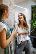 © NDABCREATIVITY - Office coffee break with two business female colleagues having fun chatting over cups of coffee