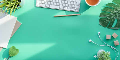 Fototapete - Flat lay of top view desk work table with Coffee computer notebook and pencil work space in minimal green color spring tone concept includes copyspace for add text or graphic