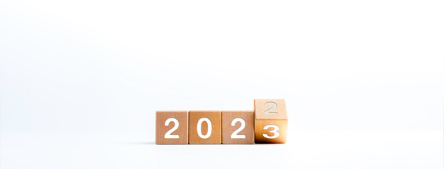 Poster - 2023 happy new year concept banner. Flipping the 2022 to 2023 year numbers calendar on wooden cube blocks isolated on white background for new year change for starting new things or new business.