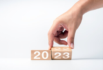 Poster - Close up hand flipping the 2022 to 2023 year numbers calendar on wooden cube blocks for preparation the new year change, begin and start new business target strategy and happy new year 2023 concept.