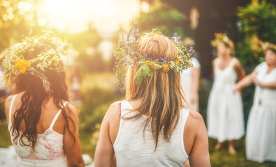 Women in flower wreath on sunny meadow, Floral crown, symbol of summer solstice.
