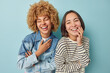 © wayhome.studio  - Happy positive diverse female friends laughs joyfully have fun smile toothily expresses sincere emotions and feelings dressed in casual outfit isolated over blue background. Friendship concept