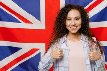 Young Smiling Happy Cheerful Black Teen Girl Foreign Student She Wear Casual Clothes Backpack Bag Show Thumb Up Stand On British Flag Background Studio Portrait High School University College Concept.