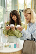 © pressmaster - Blond and brunette women choosing bodycare products while reading information on top of packages of body scrub and lotion