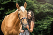 Equestrian and her horse team: Portrait of a young woman cuddle with her palomino kinsky warmblood horse. 