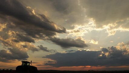 Wall Mural - Agricultural machinery works in the field at sunset