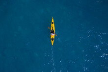 Yellow Kayak In Motion On Blue Water Top View. Yellow Canoe Movement On Water Top View.