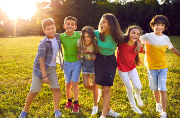 group of cheerful little kids playing in the park, enjoying summer and having fun together. bunch of