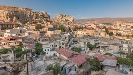 Wall Mural - Urgup Town aerial panoramic view from Temenni Hill in Cappadocia Region of Turkey timelapse. Old houses and buildings in rocks at evening before sunset