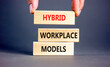 Hybrid workplace models symbol. Concept words Hybrid workplace models on wooden blocks. Businessman hand. Beautiful grey background. Business hybrid workplace models quote concept. Copy space