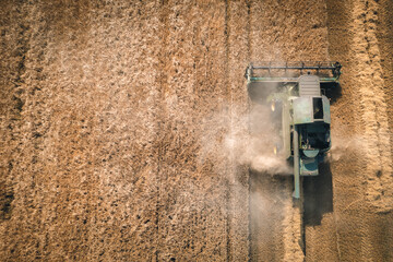 An aerial view of a combine harvester harvesting on a sunny day in Europe. 