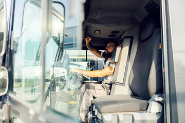 A truck driver sitting in truck and preparing to drive it.