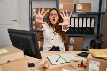 Wall Mural - Young hispanic woman working at small business ecommerce doing stop gesture with hands palms, angry and frustration expression