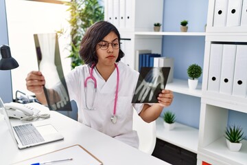 Canvas Print - Young latin woman wearing doctor uniform holding xray at clinic