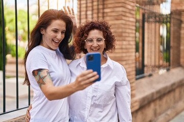 Poster - Two women mother and daughter hugging each other having video call at street