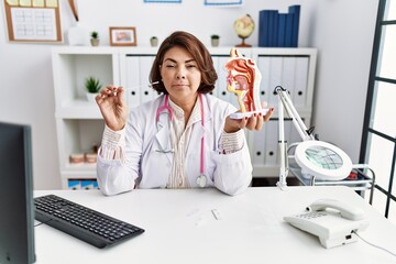 Poster - Middle age hispanic doctor woman holding coronavirus infection nasal test smiling looking to the side and staring away thinking.