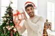 © Krakenimages.com - Young hispanic man smiling happy holding gift at home.