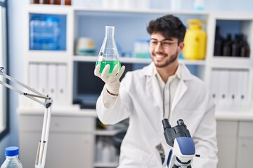 Canvas Print - Young hispanic man scientist smiling confident measuring liquid at laboratory