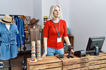 Wall Mural - Young caucasian woman smiling confident working at clothing store