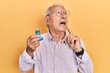 © Krakenimages.com - Senior man with grey hair holding medical asthma inhaler serious face thinking about question with hand on chin, thoughtful about confusing idea