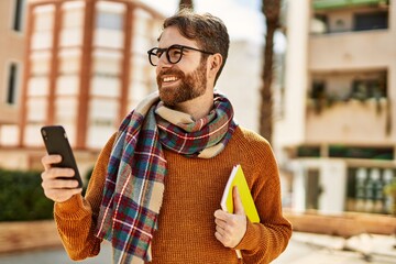 Wall Mural - young caucasian man with beard  using smartphone outdoors on a sunny day